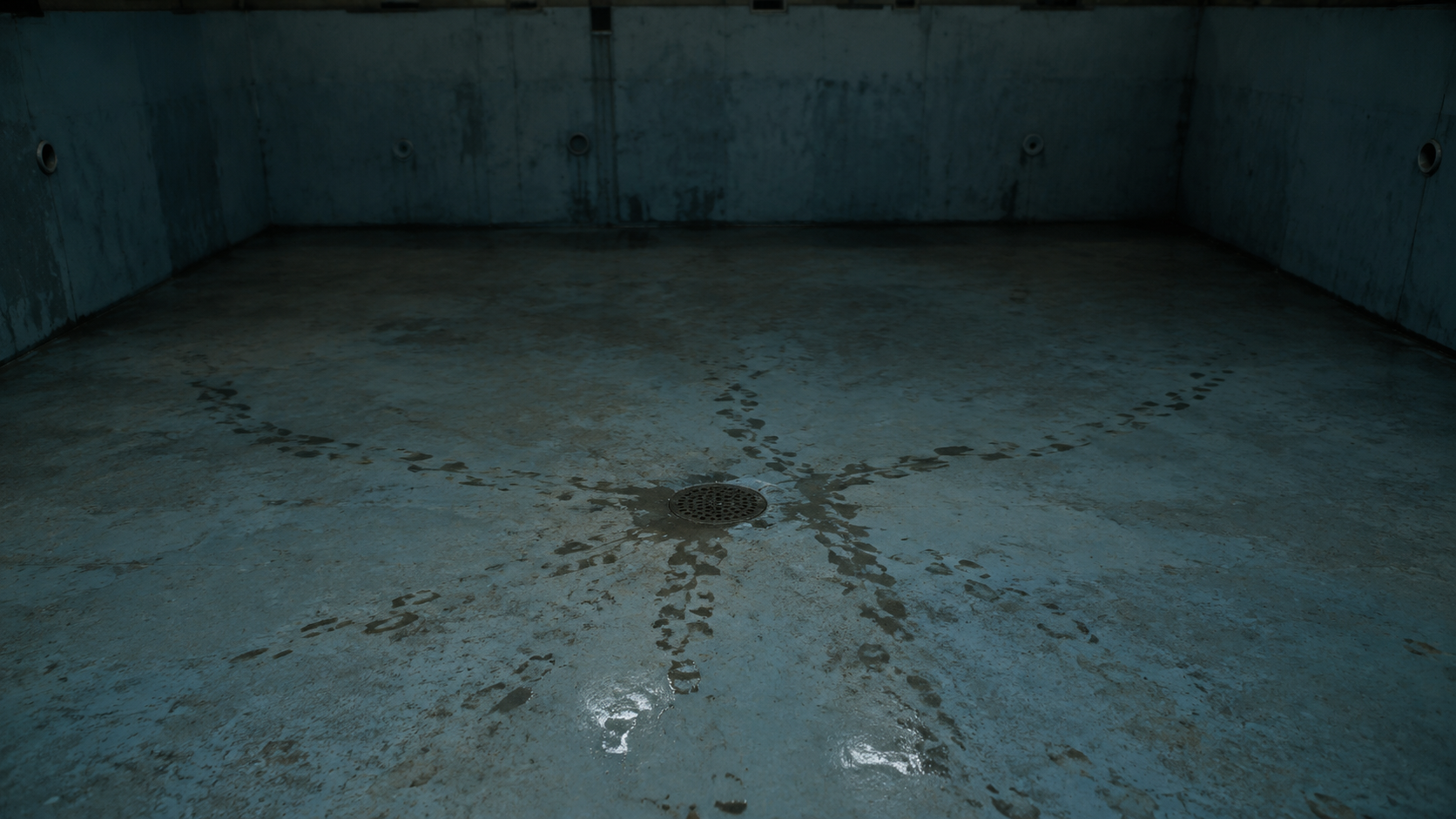 Footprints end beside the drain at the deep end of an empty pool.