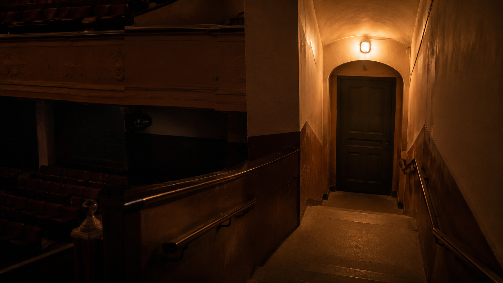 A dim theater balcony stairwell and exit door
