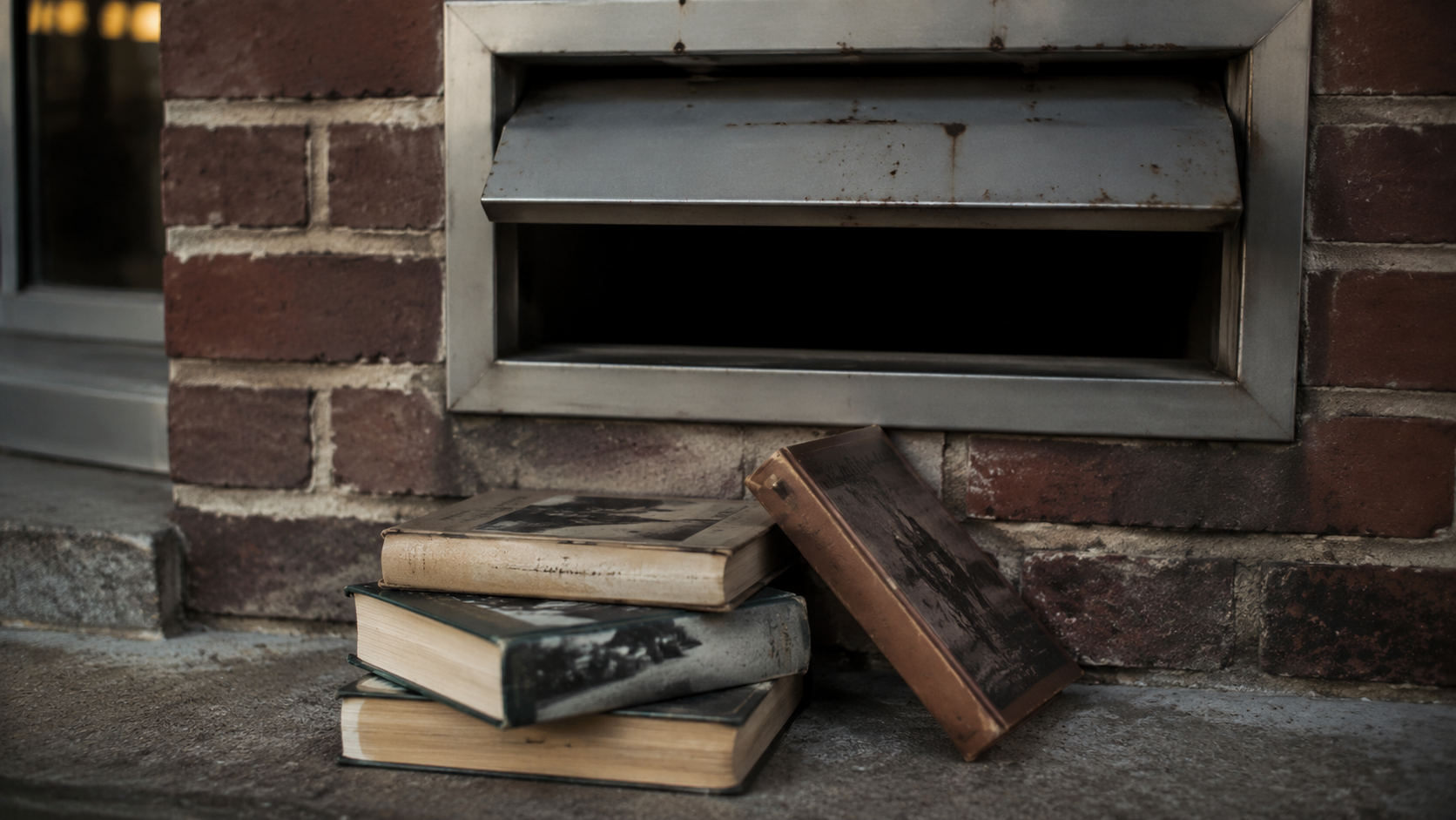 Old local-history books lying beneath a locked library return slot.