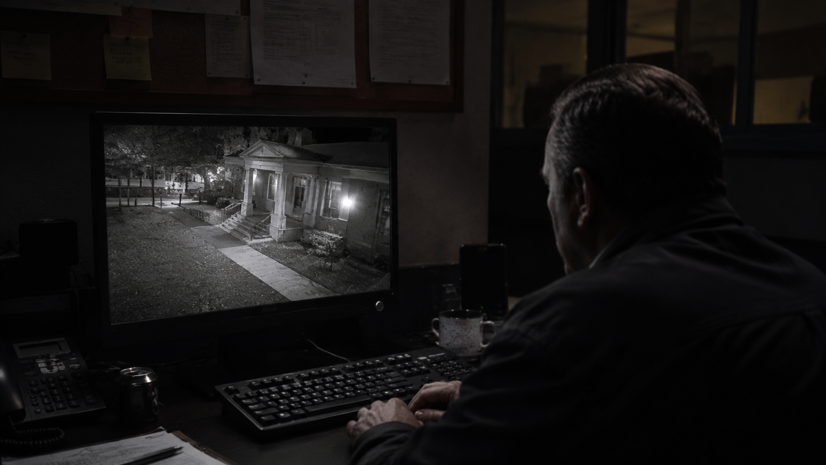 Night staff reviewing a grainy library security camera feed.