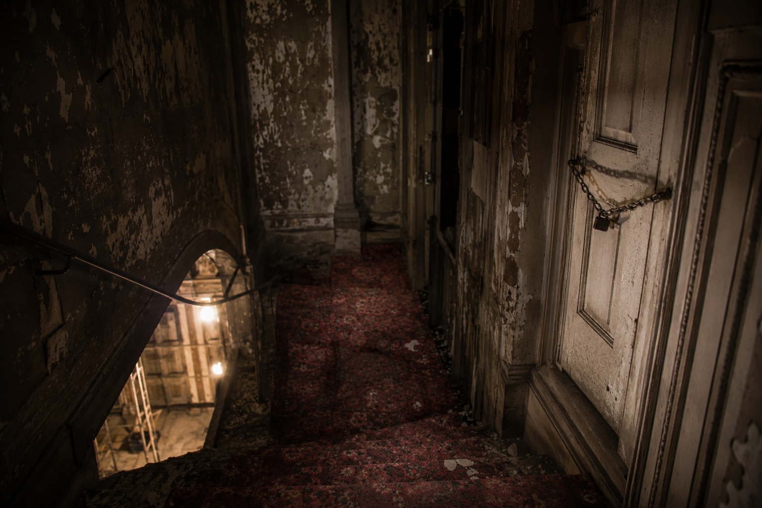 A chained balcony stairwell door in an abandoned theater blocks access to the upper level.