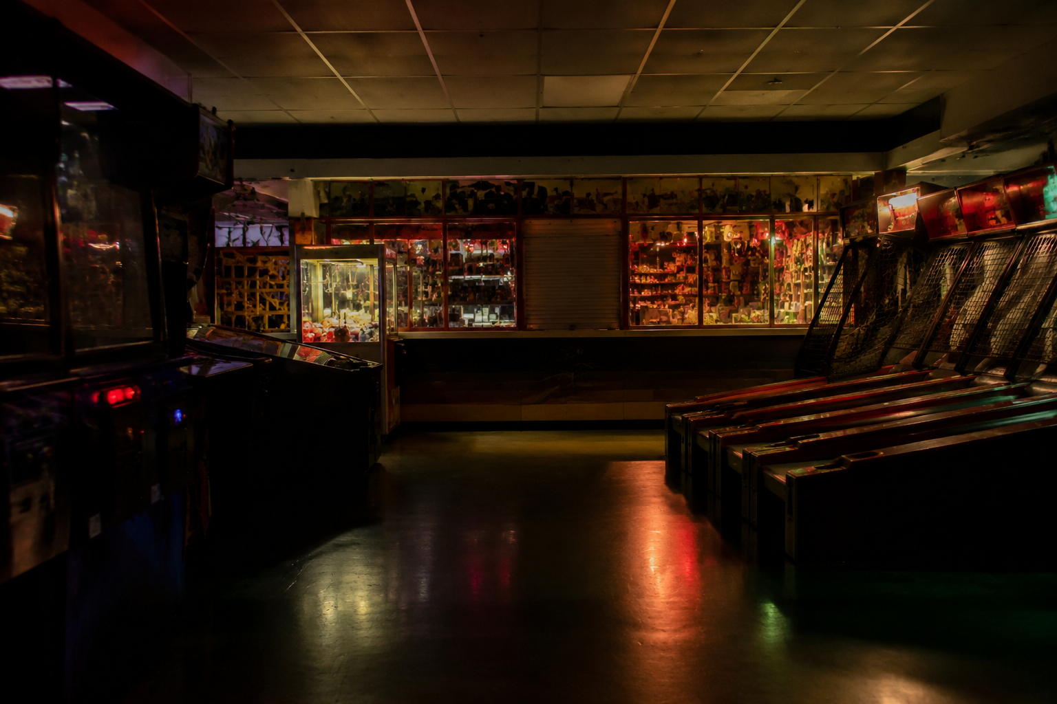 Dark arcade machines facing a closed redemption desk after hours