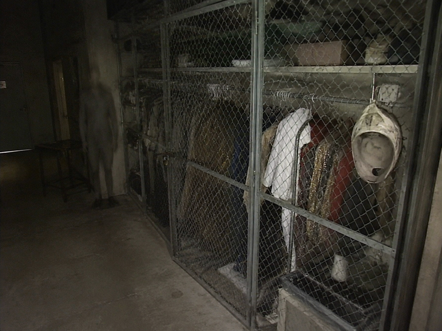 After-hours security camera view of a costume cage with one mask turned backwards