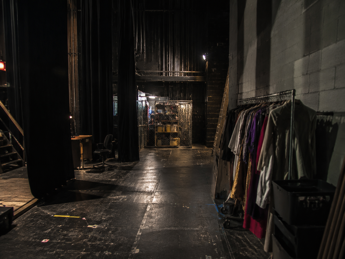 Empty theater stage wing with costume cage shadows after closing