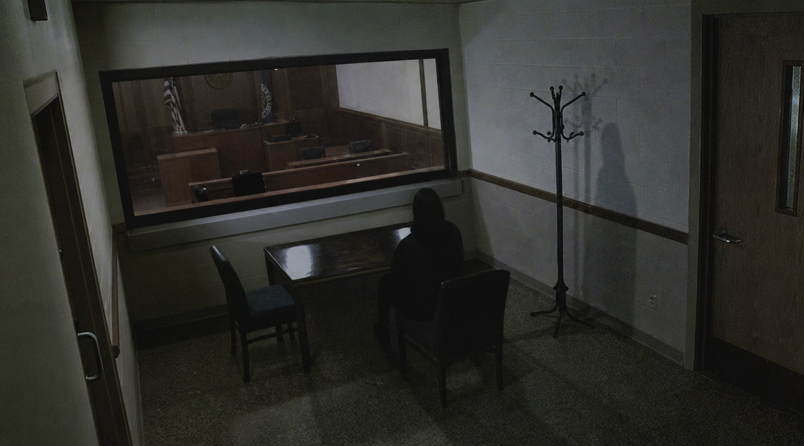 Dark seated shape near courthouse coat rack