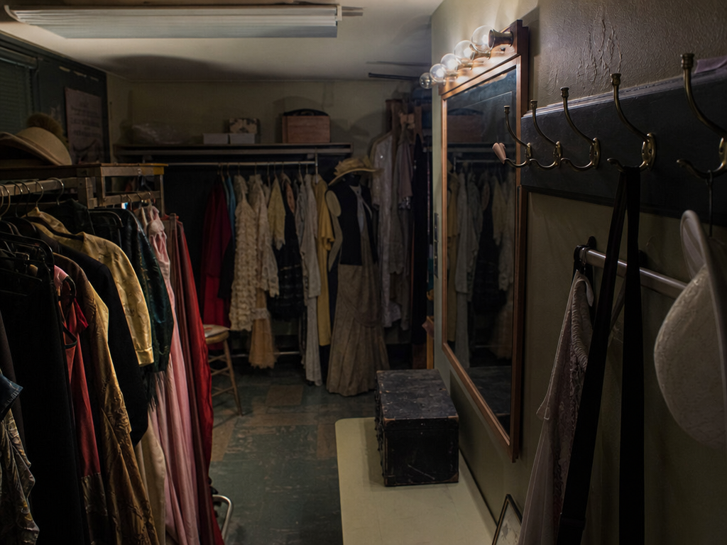 Dim community theater costume room after lockup