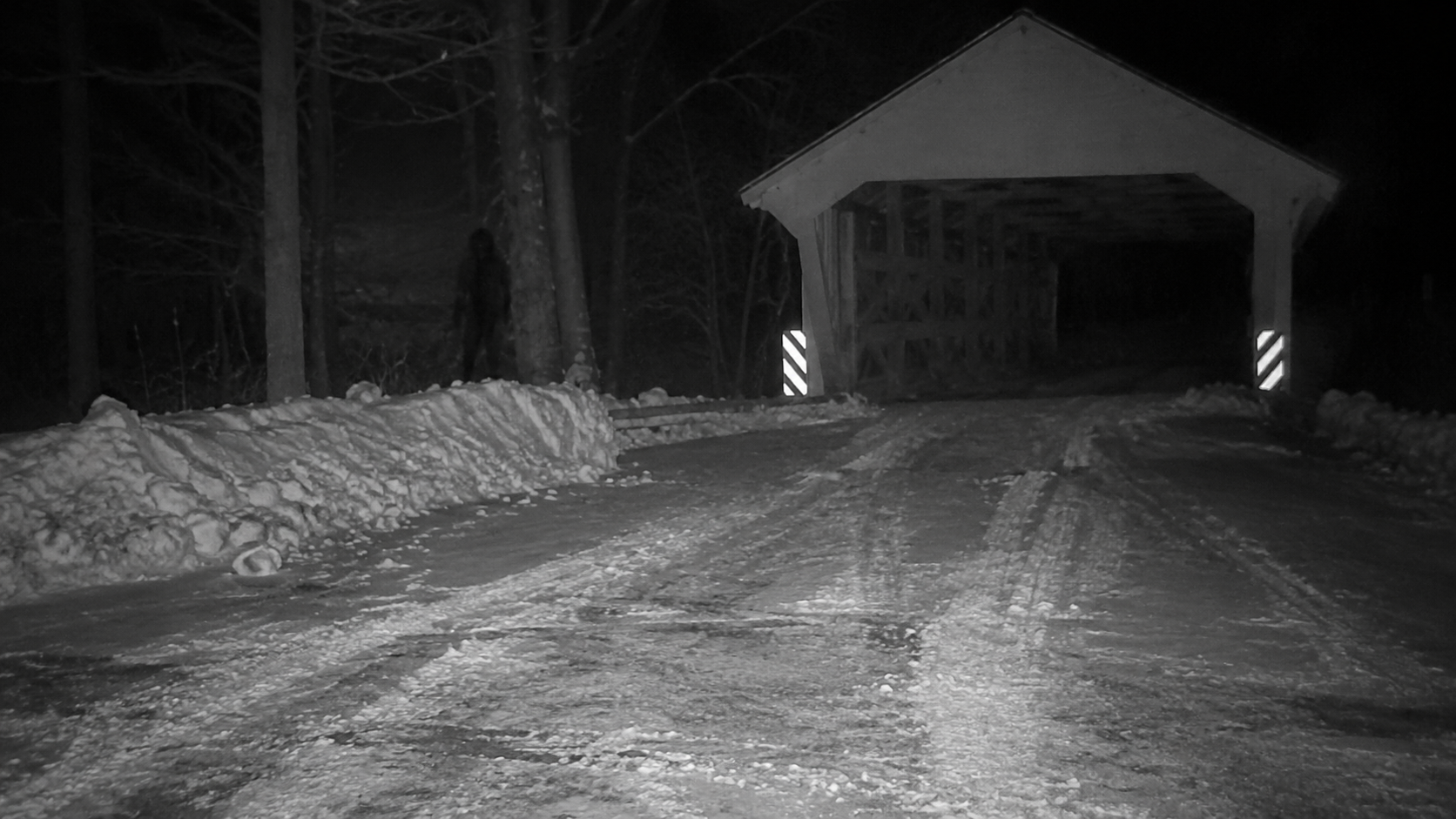 Dark upright shape near snowy covered bridge turnaround