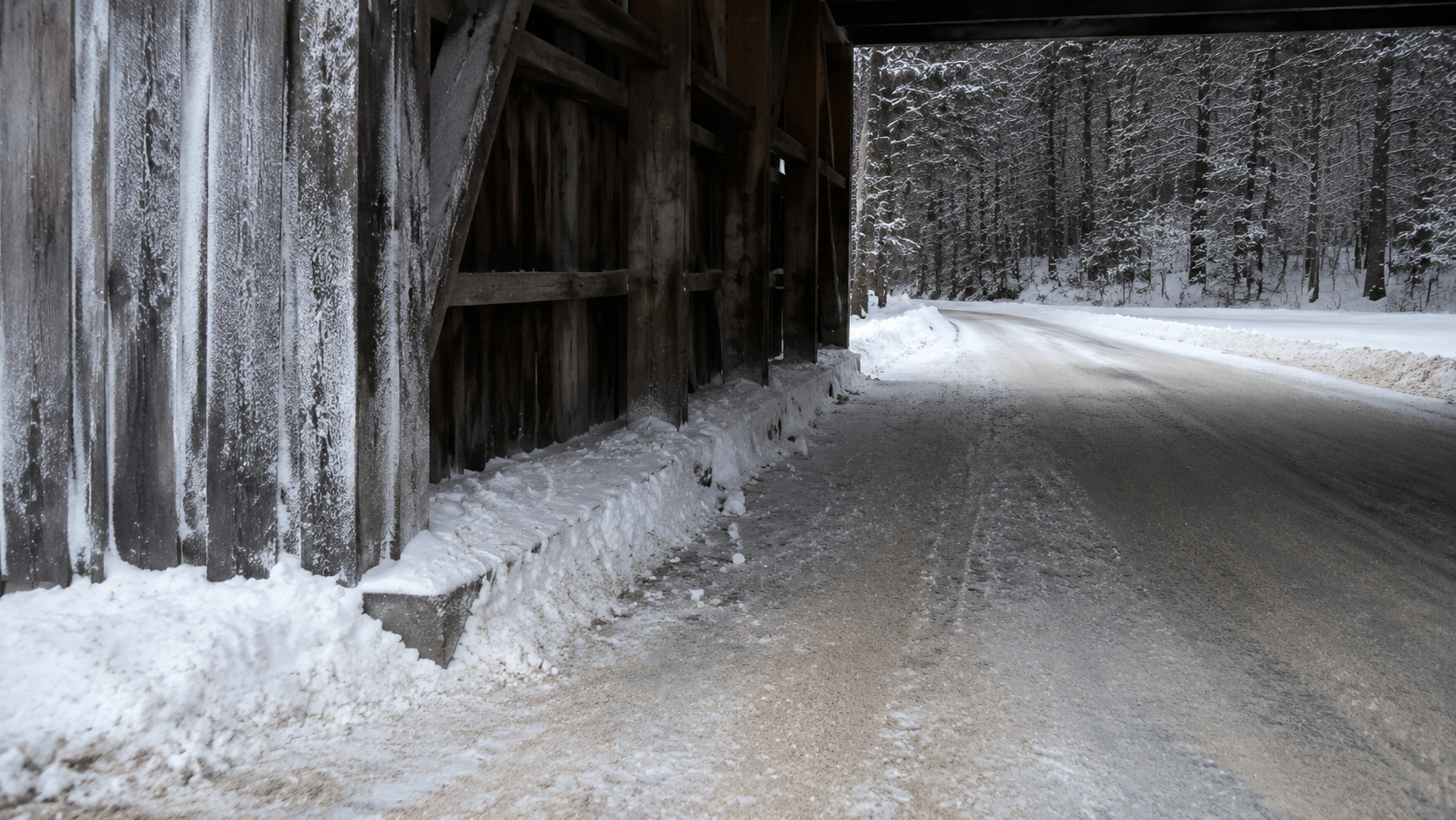 Packed snow line beneath a covered bridge entrance
