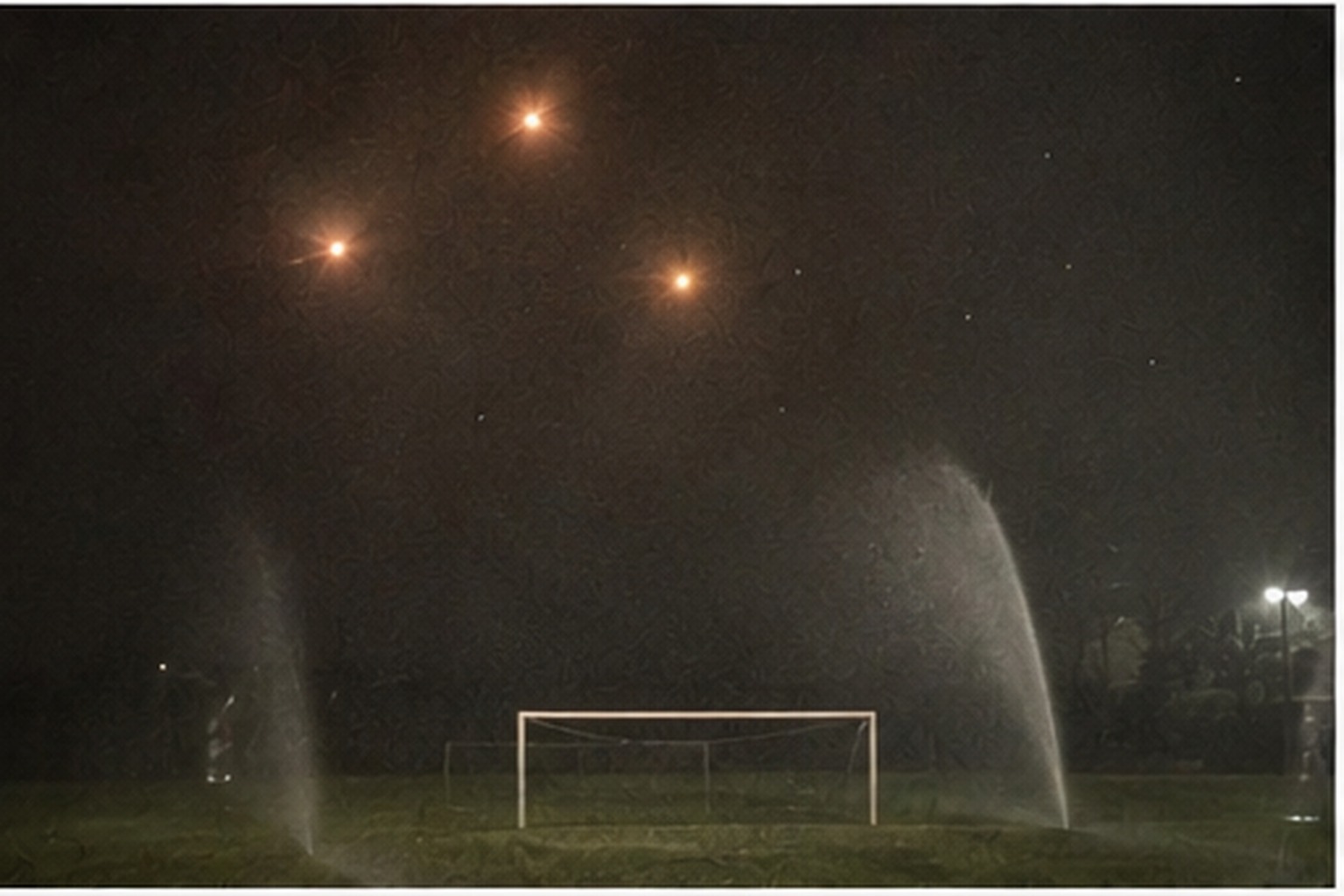 Phone zoom of orange lights above a soccer goal
