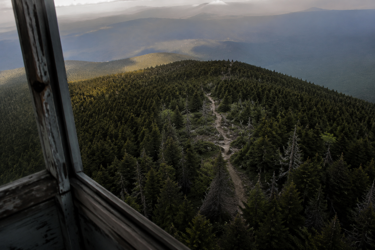 View from an old fire tower over a wooded trail and ridgeline