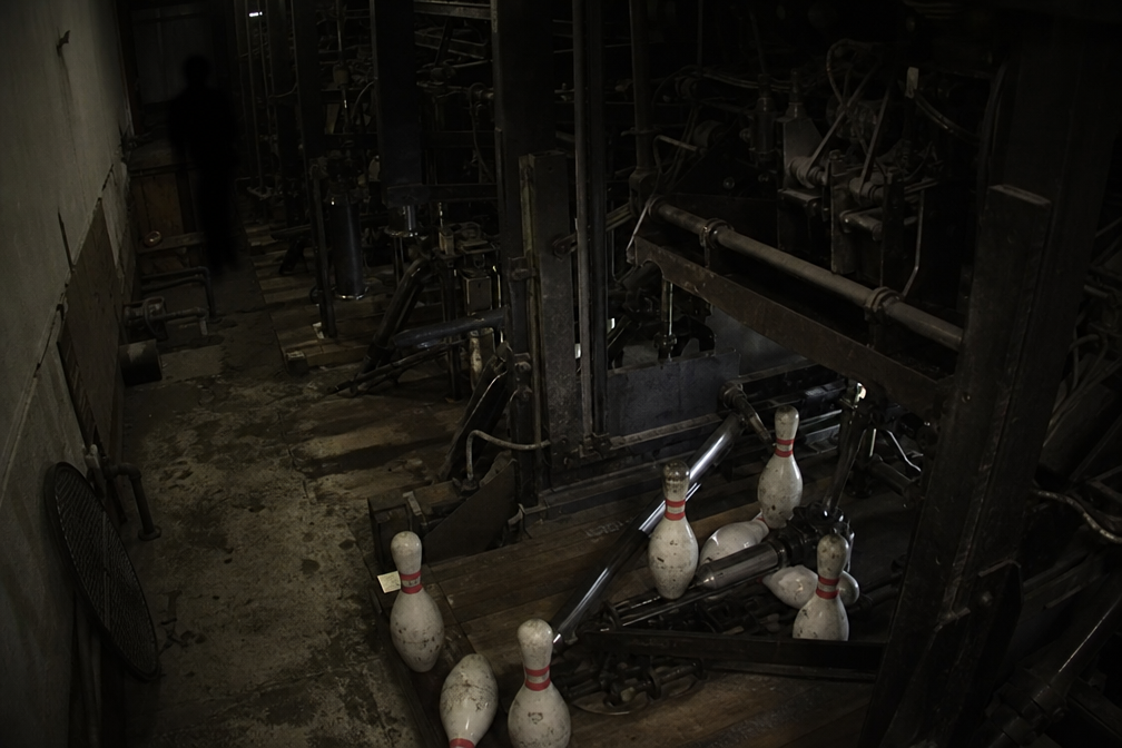 Dark figure partly hidden behind pinsetter elevator