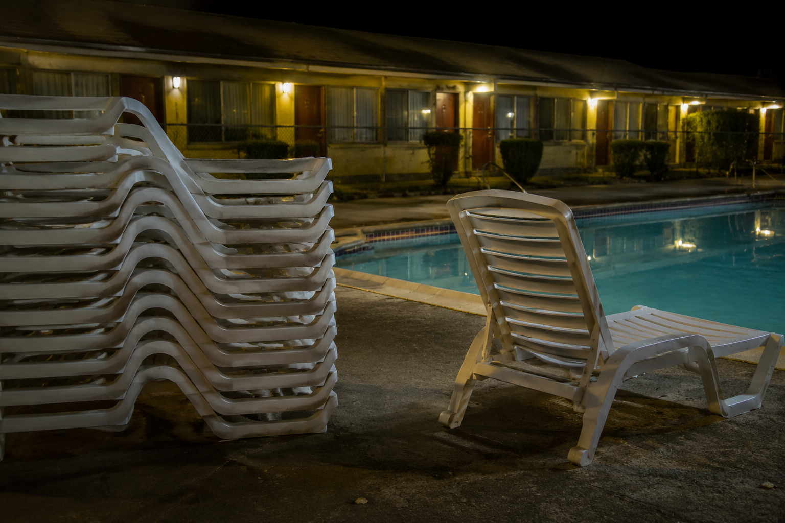 Stacked motel pool chairs with one chair turned out of line