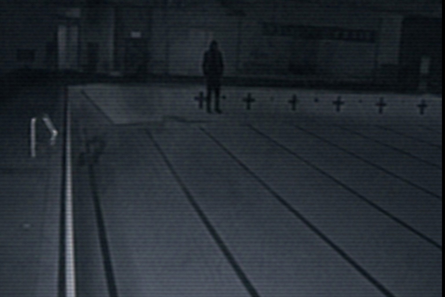Dark figure beyond drained pool lanes