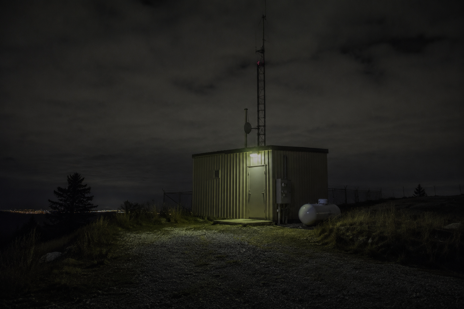 Old mountain lookout payphone near a closed road with a radio tower on the ridge