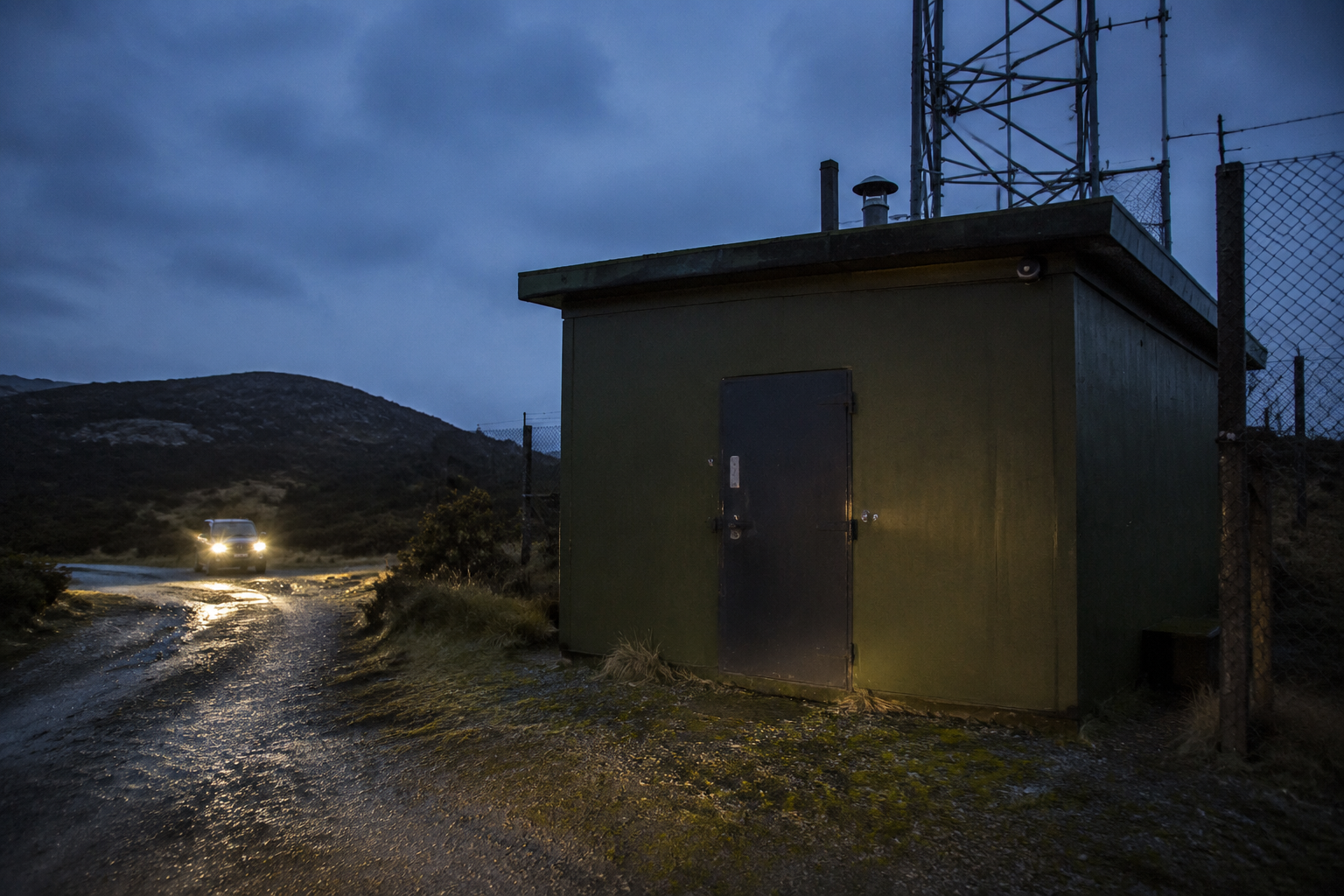 Weathered outdoor payphone at a mountain lookout with tower reflection in glass