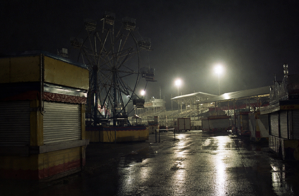 Empty rainy fair midway near grandstand lights