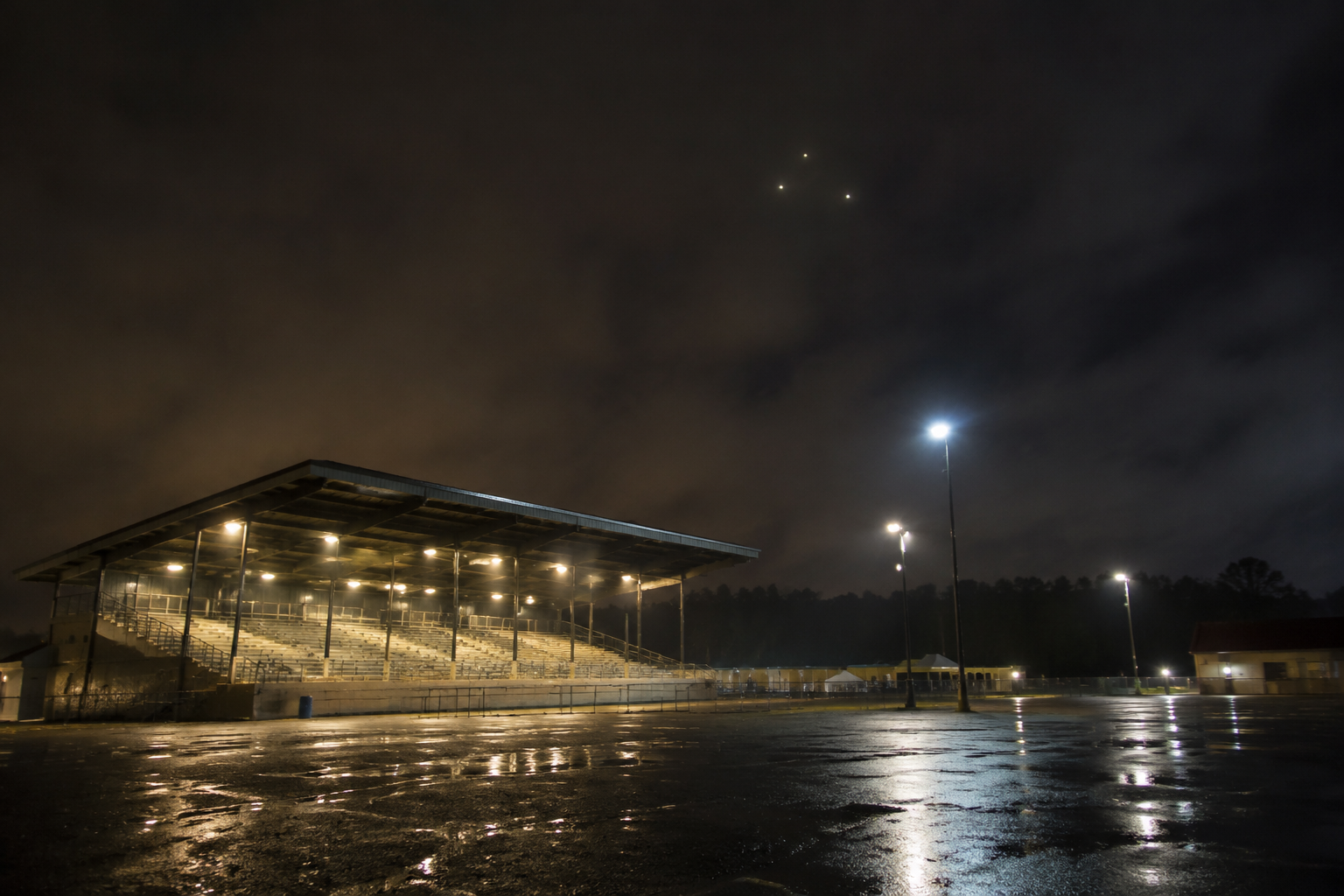 Three faint lights above a rainy grandstand