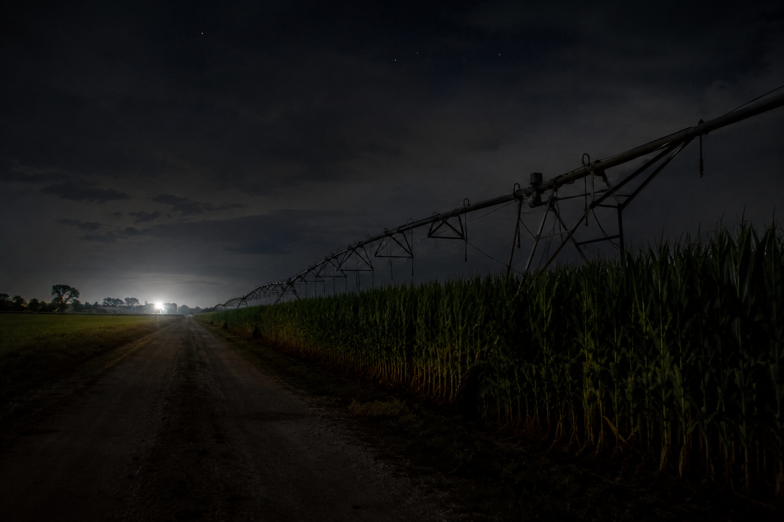 Empty cornfield service road beside irrigation pivot at night