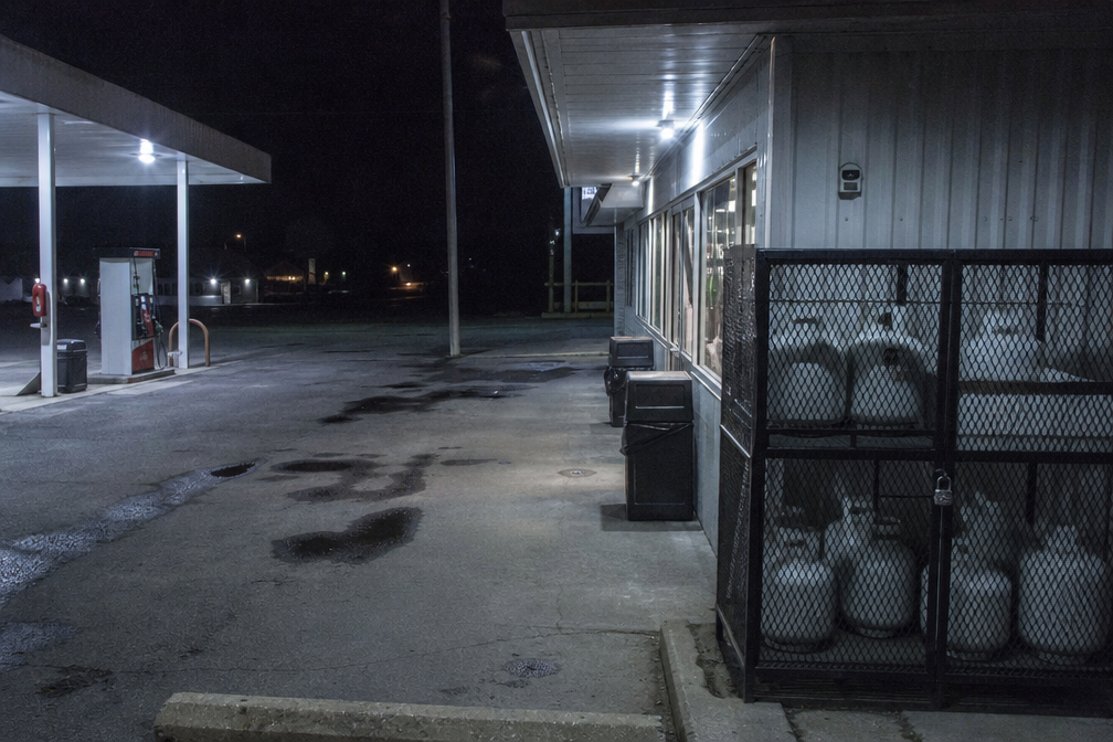 Blue light glowing over a rural propane exchange cage at night.