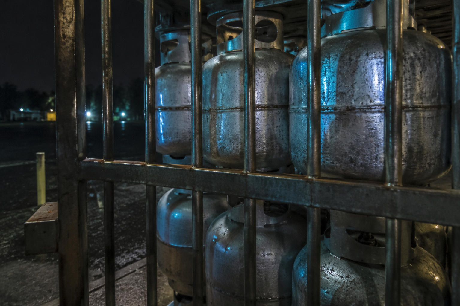 Propane cage bars and tank racks reflecting a blue service light.