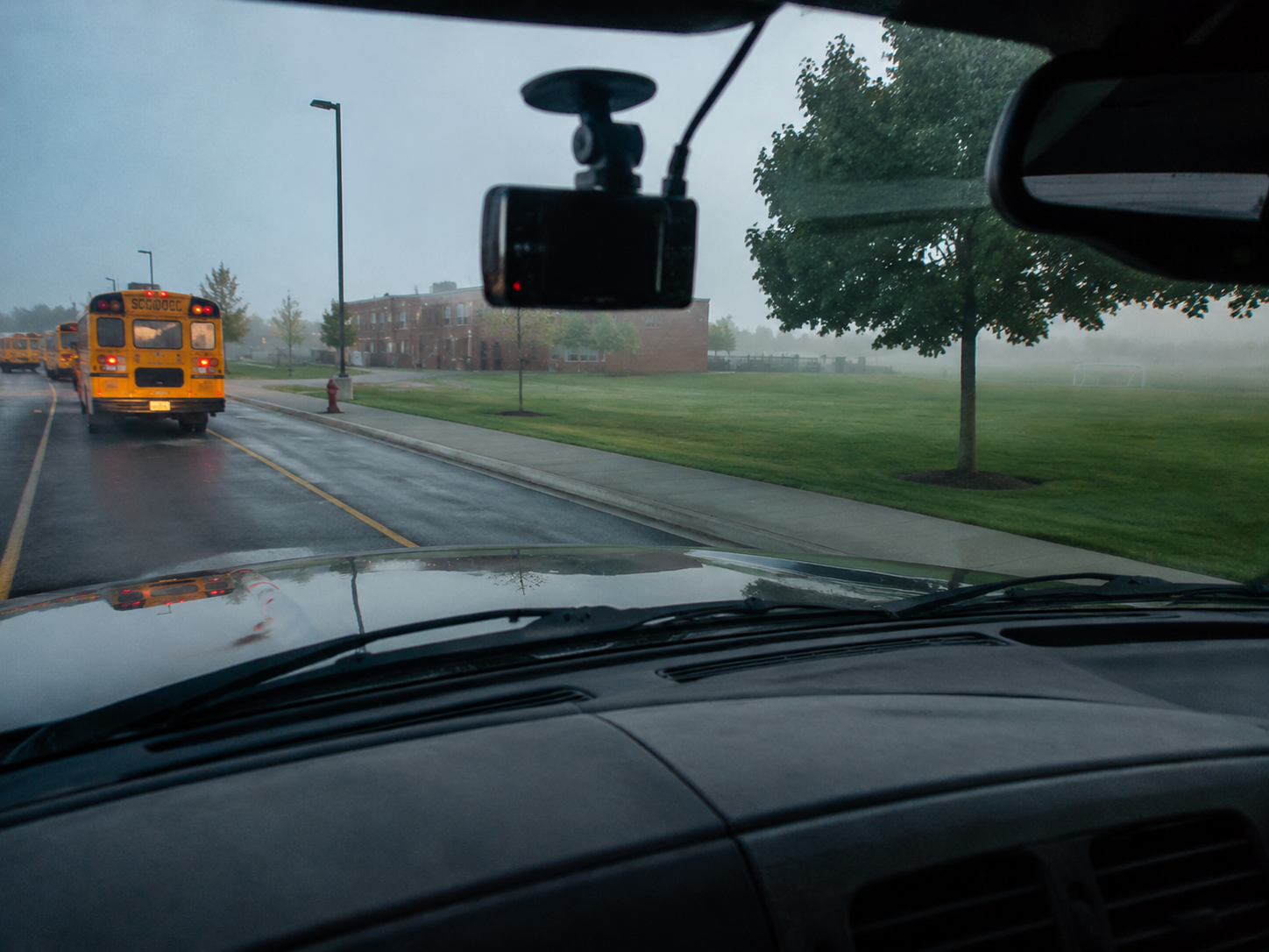A dashboard camera points toward a quiet school bus loop after hours.