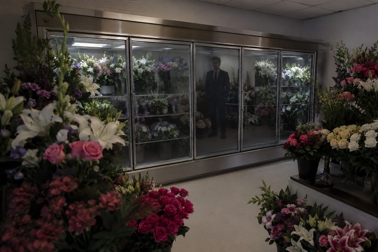 Editorial recreation of the Funeral Home Flower Room Camera Showed A Man In A Dark Suit Behind The Refrigerated Case story, image 1.