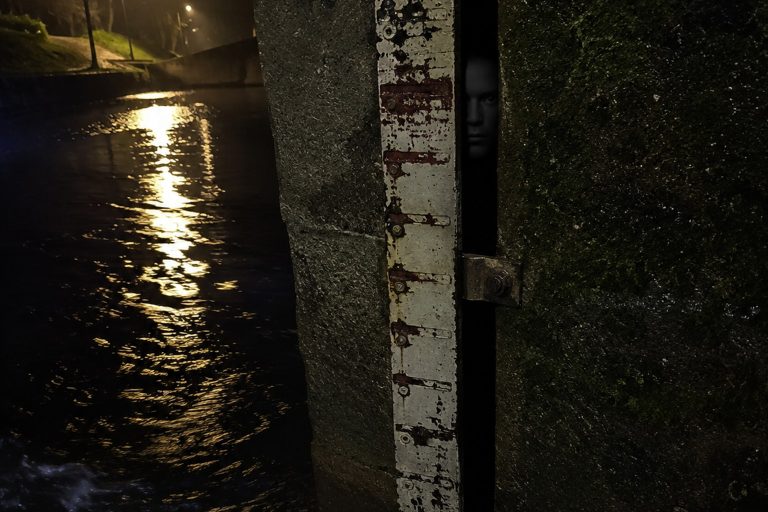 Editorial recreation of the Night Walk Photo On The Canal Footbridge Showed A Face Behind The Flood Gauge story, image 1.