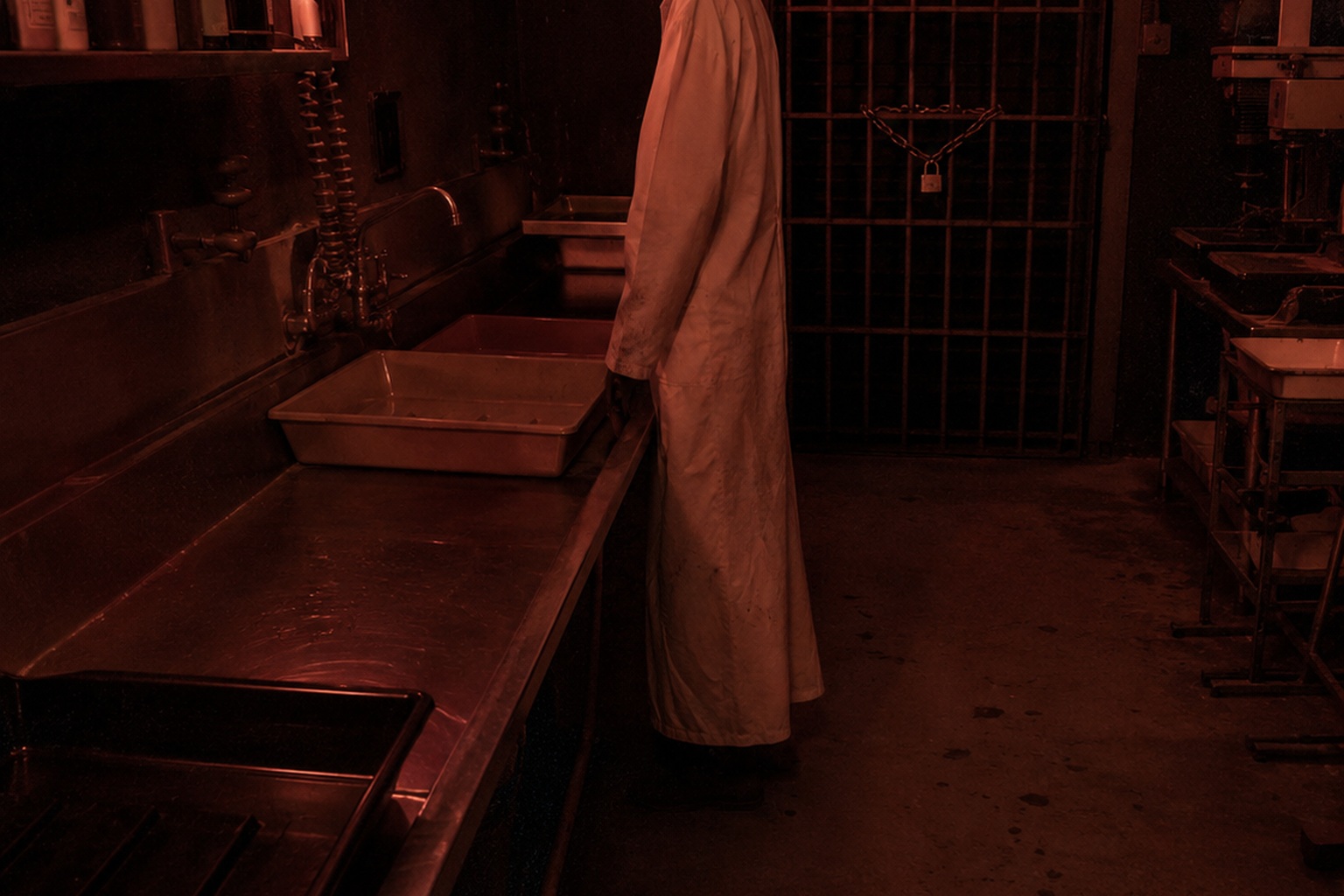 Editorial recreation of the Old Photo Lab Darkroom Camera Showed A White Apron Figure Standing Beside The Developing Sink story, image 1.