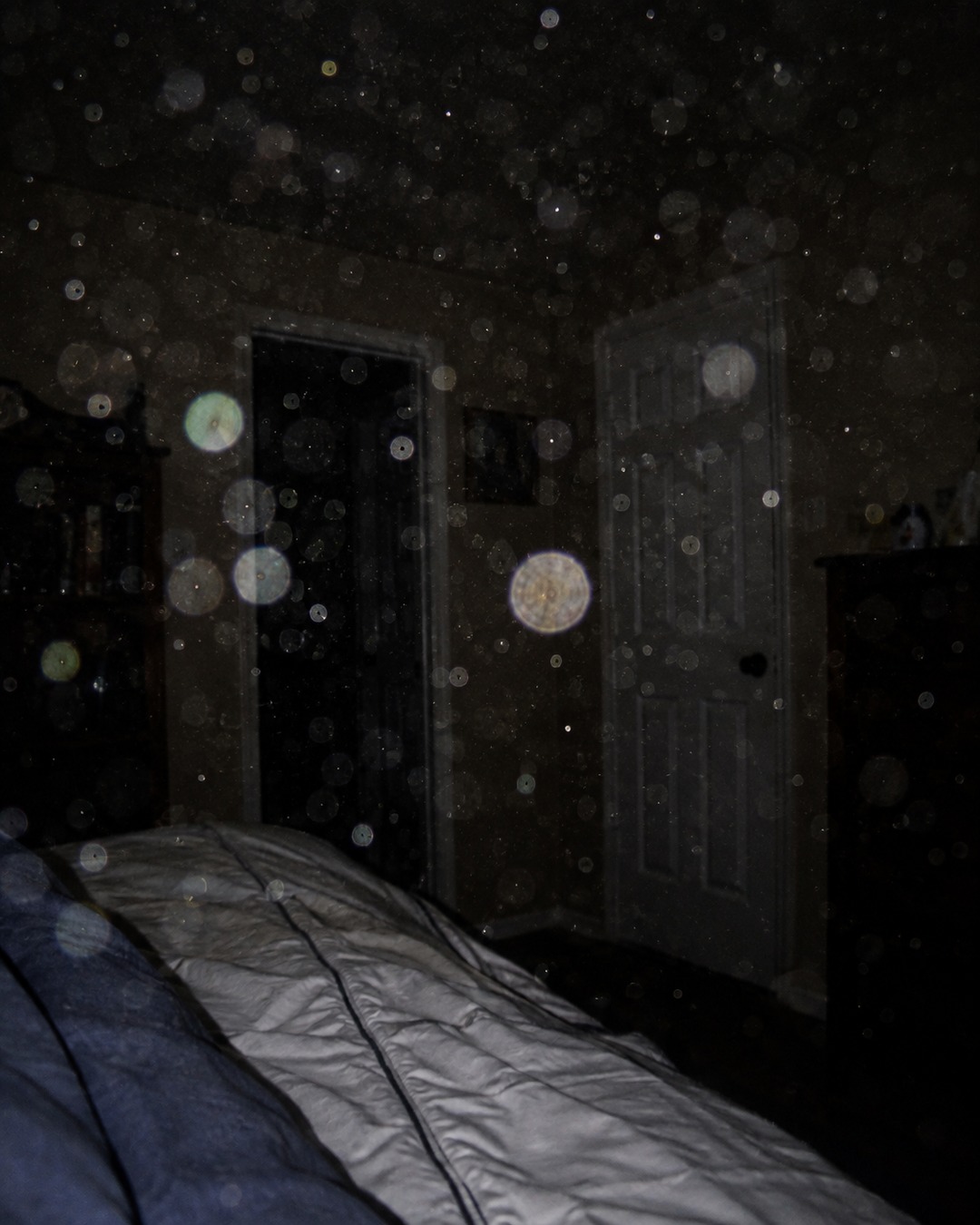 Editorial illustration of dust or moisture lit by camera flash in a dark room.